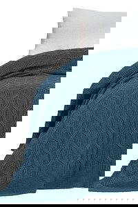 DAPHNE Samira Pleteni Prekrivač u indigo plavoj boji na krevetu sa bijelim jastucima, elegantan i udoban tekstil za modernu spavaću sobu.