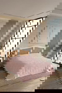 Visoka moderna spavaća soba s velikim prozorima, minimalističkim dizajnom i elegantnim ukrasima, idealna za opuštanje i odmor, prikazuje estetski ugodan prostor za relaksaciju.