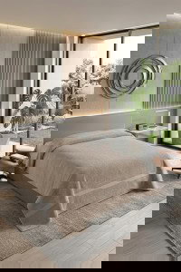 Bež frotirna deka od 100% pamuka, prebačena preko kreveta, sa vidljivom teksturom frotira i diskretnim prugama.