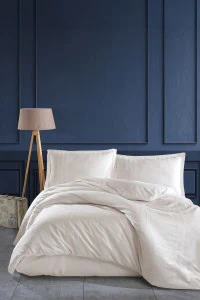 Visoka kvaliteta pamuk posteljina u bež boji na modernoj spavaćoj sobi sa tamnoplavim zidom, idealna za udoban san i elegantan izgled.