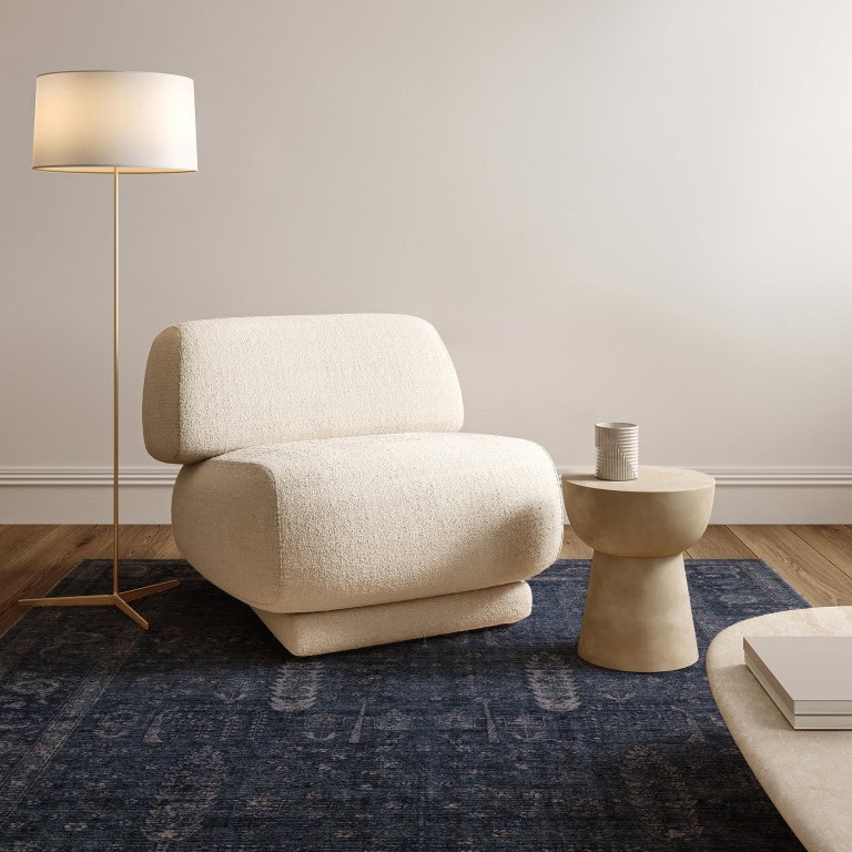 Sef fotelja u neutralnim tonovima s modernim dizajnom, smještena na tamnoplavom tepisu u minimalističkom prostoru. Idealno za udobno sjedenje i elegantan interijer.