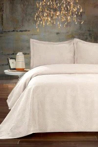 Umetnička fotografija bež prekrivača "Vicenza" na krevetu u modernom enterijeru, prikazuje teksturirani set za udoban i elegantan izgled spavaće sobe.